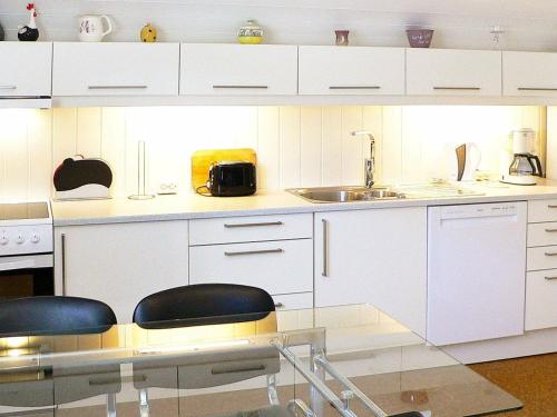uma cozinha com armários brancos, um lavatório e cadeiras em Holiday Home Sørbøvåg II em Sørbø