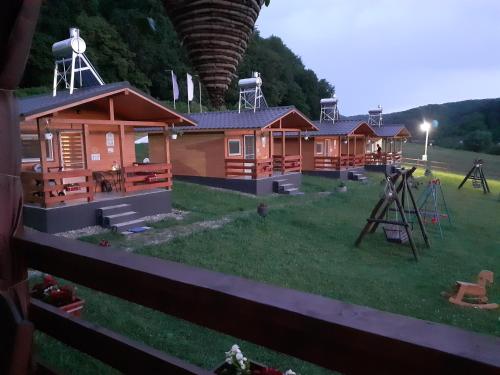 una fila de lodges de madera con parque infantil en Dara's Camping en Prod