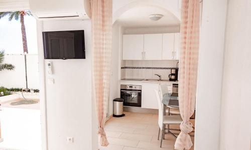 a small kitchen with white cabinets and a table at Hotel et Appartements Reine D'Azur in Roquebrune-Cap-Martin