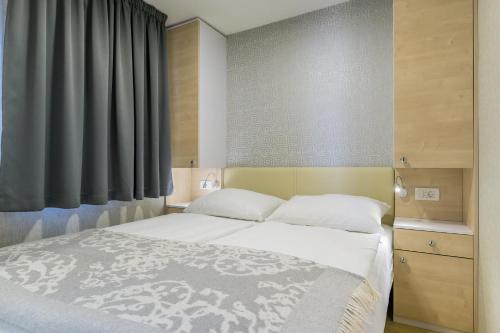 a bedroom with a white bed with a window at Mobile Homes Krk Silo in Šilo