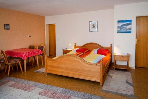 a bedroom with a large wooden bed and a table at Ferienwohnungen mit Alpensicht in Lindau
