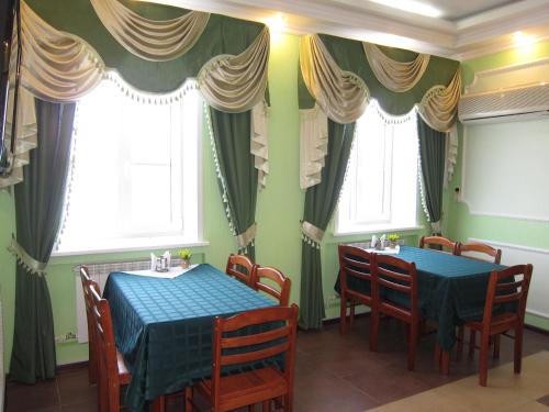 duas mesas num restaurante com paredes verdes e janelas em Guest center-hotel Myshk Inn em Myshkin