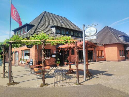 a building with tables and chairs in front of it at Hotel Rüstersieler Hof in Wilhelmshaven