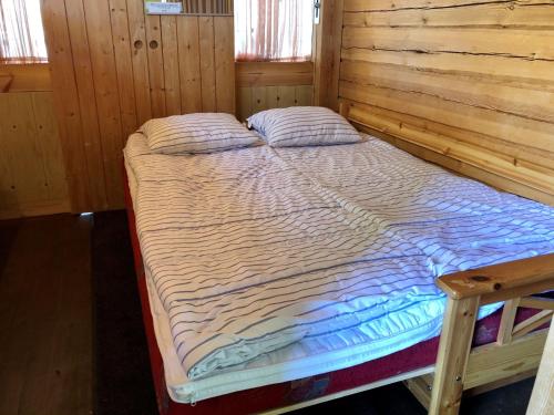 Bett in einem Zimmer mit Holzwänden in der Unterkunft Kyly in Savonlinna