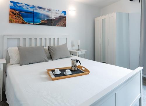 a white bedroom with a white bed with a tray on it at Casa a primera linea de mar in Costa Teguise