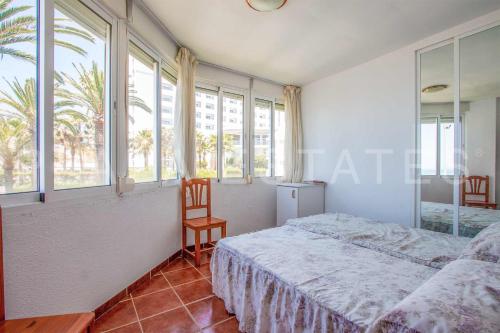 - une chambre avec un lit, une chaise et des fenêtres dans l'établissement Apartamento en Edificio Torresol, 1ª linea de playa en Nerja, à Nerja
