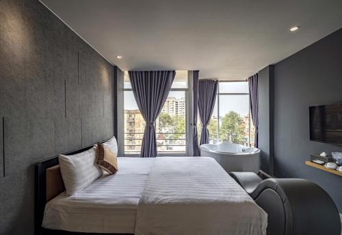 a bedroom with a bed and a tub and a window at Bonita Boutique Hotel in Ho Chi Minh City
