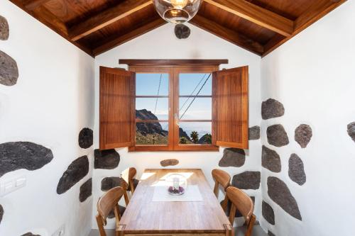 Un comedor con mesa y sillas de madera. en TenoHomes The Sunset Escape in Carrizales, Masca, en Buenavista del Norte