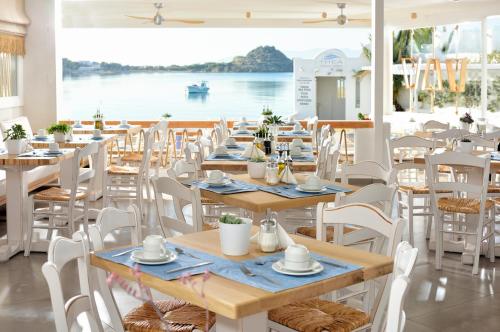 un ristorante con tavoli e sedie con vista sull'acqua di Petinos Hotel a Platis Yalos