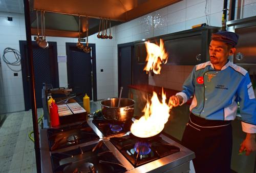 a man in a kitchen with fire on a stove at Hotel Sultansaray Sultanhanı in Sultanhanı