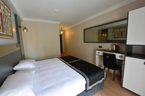 a bedroom with a bed and a desk and a kitchen at Hotel Sultansaray Sultanhanı in Sultanhanı