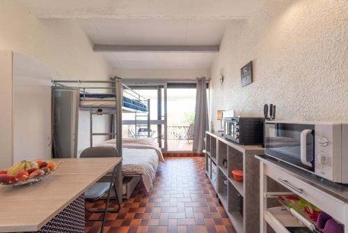 a room with a bed and a kitchen with a table at La Dune in Leucate