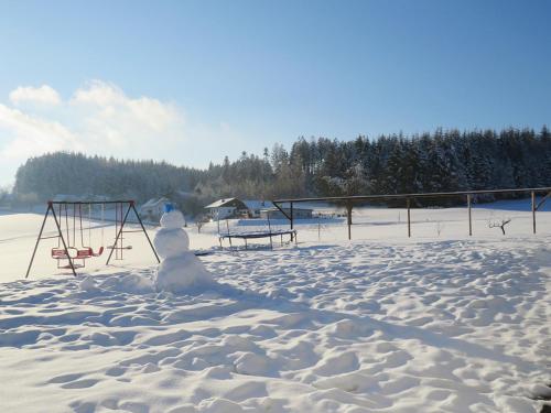 a snowman sitting in the snow next to a playground at Traumferienhaus XXL Ortner in Wetzendorf