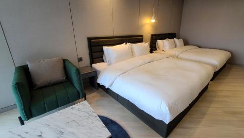 a bedroom with two beds and a green chair at Hotel Ohevday in Namwon