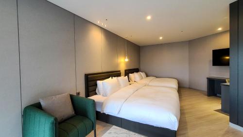 a bedroom with a large bed and a green chair at Hotel Ohevday in Namwon