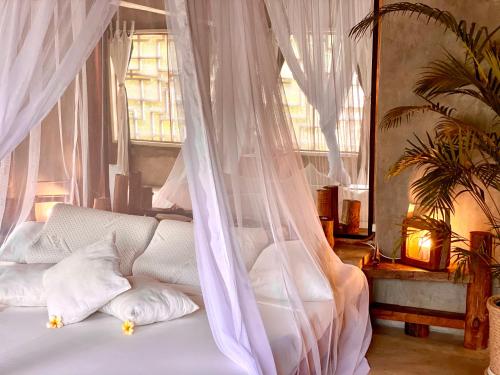 a bedroom with a white bed with a mosquito net at Rock and Sea Resort in Watamu