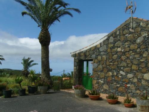 a stone building with a palm tree in front of it at Casas Rurales Amparo Las Hayas in Valle Gran Rey
