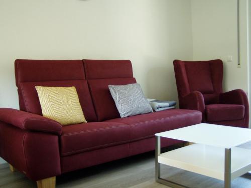 a living room with a red couch and a chair at Weinhaus Lenartz-Bleser in Briedern