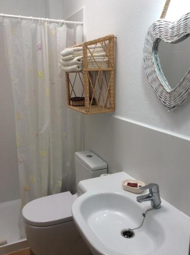 ein Badezimmer mit einem Waschbecken, einem WC und einem Spiegel in der Unterkunft VIVIENDAS ES CARNATGE in Playa Migjorn