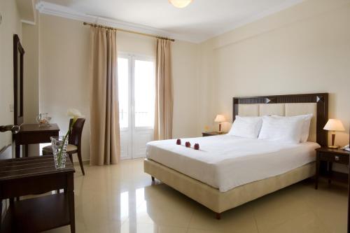a bedroom with a large white bed and a desk and a bed sidx sidx sidx at Royal Nidri in Nydri