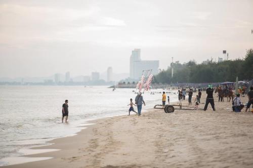 a group of people walking on the beach at TK Guesthouse in Cha Am