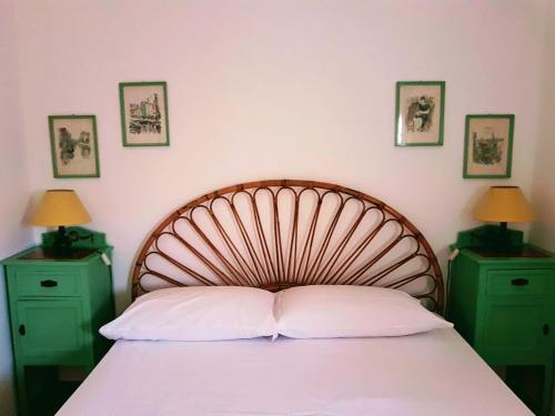 a bed with a wooden headboard and two green night stands at Casa al Mulino in San Vito lo Capo