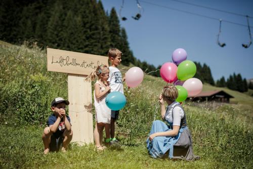 a group of children standing next to a sign with balloons at Hotel Stäfeli in Lech am Arlberg