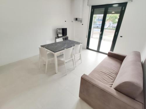 een woonkamer met een bank en een tafel en stoelen bij QUITO - Appena Ristrutturato - Dietro Piazza Mazzini - Immbil Relax in Lido di Jesolo