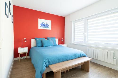 um quarto com uma cama azul e uma parede vermelha em "Les Mouettes" em Boulogne-sur-Mer