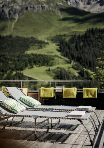 a table and chairs on a deck with a view at Hotel Stäfeli in Lech am Arlberg