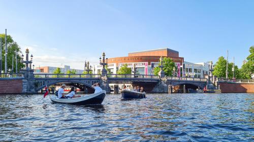 two boats in the water near a bridge at Hotel Alexander in Amsterdam
