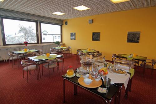 een eetkamer met tafels, stoelen en ramen bij Hotel Sunny Side Up in Dauchingen