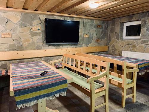a room with a table and a tv and a bench at Penzion pod Brehom in Terchová
