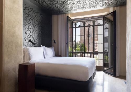 
a bedroom with a large bed and a large window at EME Catedral Hotel in Seville
