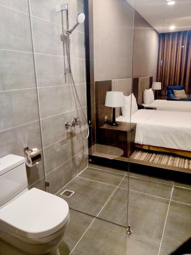 a bathroom with a shower and a toilet and a bed at Muong Thanh Luxury Saigon Hotel in Ho Chi Minh City