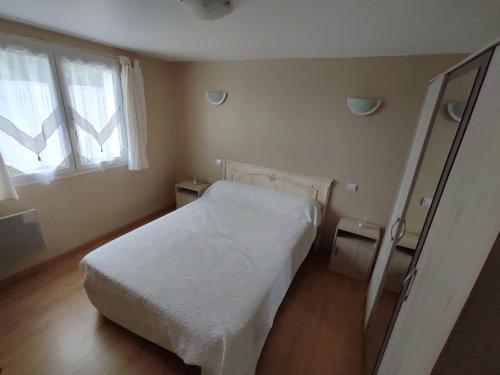 um quarto com uma cama branca e uma janela em Le Gîte du Moulin à Vent em Plazac