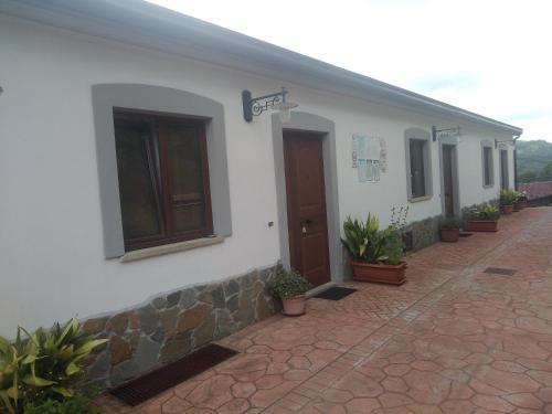 a white building with potted plants on the side of it at Azienda Agrituristica Le Prunelle in Cannalonga
