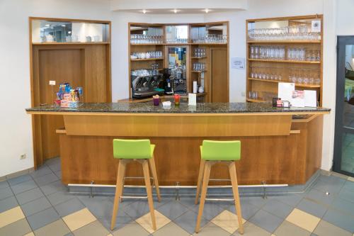 a bar in a pharmacy with two green bar stools at Am Spiegeln dialog.hotel.wien in Vienna