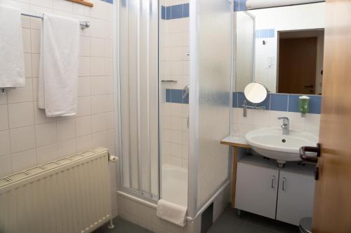 La salle de bains est pourvue d'un lavabo et d'une douche. dans l'établissement Am Spiegeln dialog.hotel.wien, à Vienne