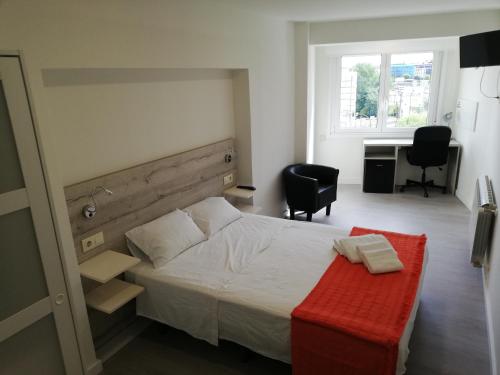 1 dormitorio con 1 cama con banco rojo y escritorio en Pensión La Intermodal, en Santiago de Compostela