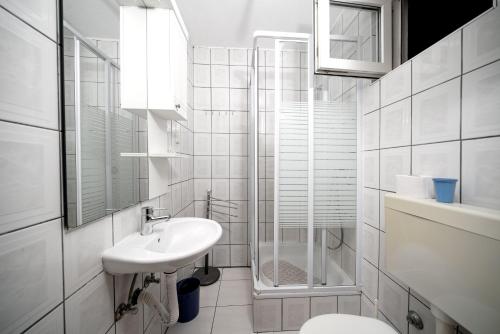 a white bathroom with a sink and a shower at Apartmani Križanović in Vodice
