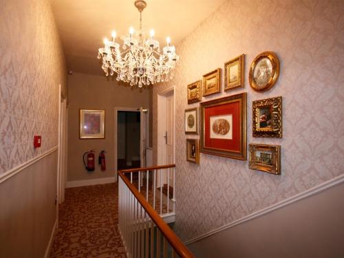a hallway with a chandelier and pictures on the wall at Colchester Boutique Hotel in Colchester