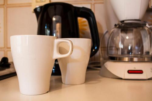 two white cups sitting on a counter next to a blender at Taonasi Taormina Apartments in Taormina