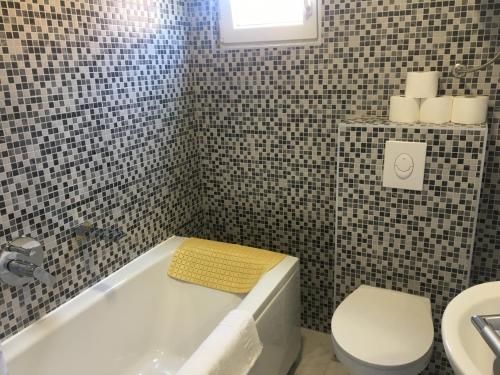a bathroom with a tub and a toilet and a sink at RIVA Seafront holiday apartments in Rogoznica