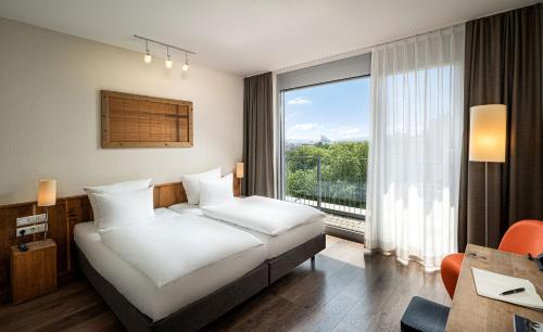 フランクフルト・アム・マインにあるマインハウス スタトホテル フランクフルトのベッドと大きな窓が備わるホテルルームです。