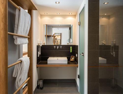 ein Bad mit einem Waschbecken und einem Spiegel in der Unterkunft mainhaus Stadthotel Frankfurt in Frankfurt am Main