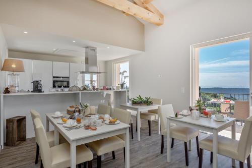 comedor con mesas y sillas blancas y cocina en Histoires de Bastide, en Tourrettes-sur-Loup