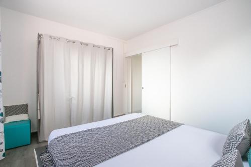 a white bedroom with a bed and a window at Le Brin d'Amour Apartment in La Trinité