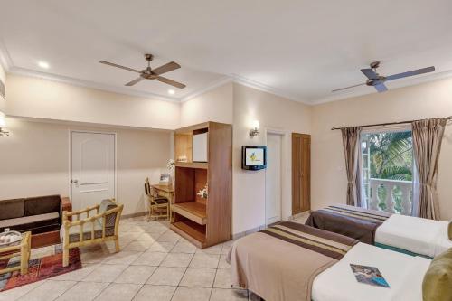 a hotel room with two beds and a television at Club Mahindra Emerald Palms, Goa in Varca