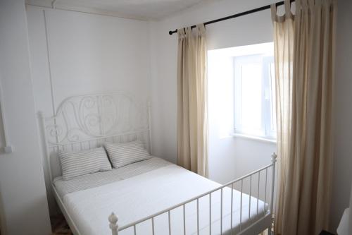 Habitación blanca con cama y ventana en Salema Beach Home, en Salema